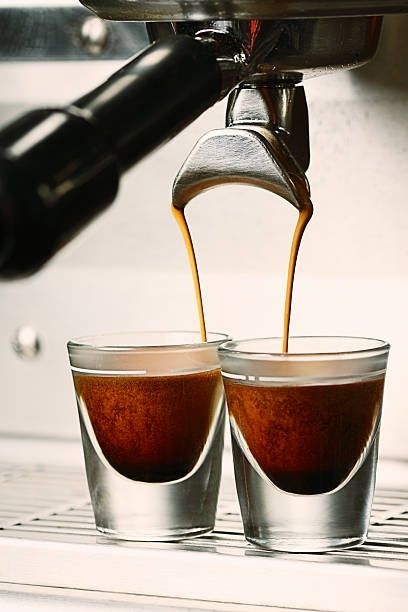 Espressomaschine brüht zwei Tassen mit gleichmäßigen Kaffeefäden