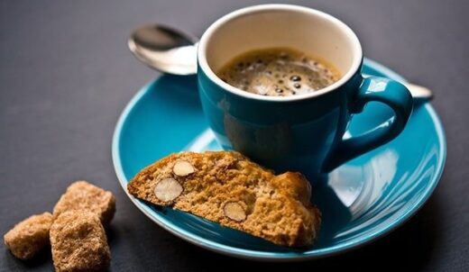 Tasse Espresso mit Cantuccini auf einem türkisfarbenen Teller