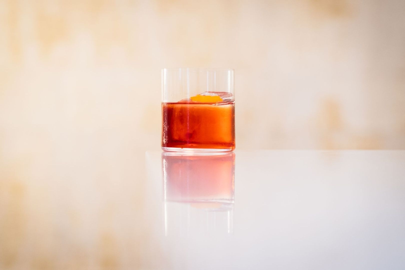 Roter Wermut im Glas mit Eis und orangefarbener Zitruszeste